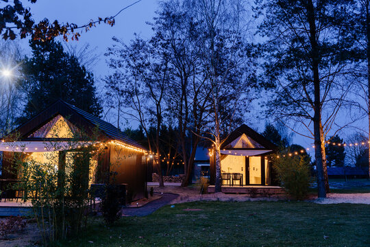 Modern tiny cabins glowing with warm lights in peaceful wooded retreat during blue hour