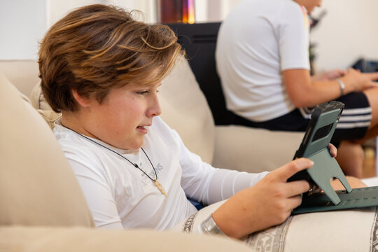 two pre teen boys gaming at home on a tablet