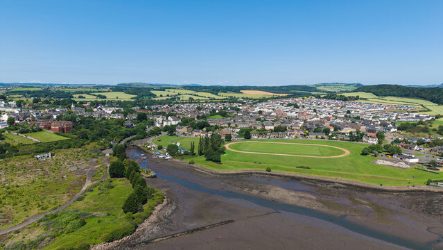 Aerial view of the coastal village of Inverkeithing in Fife, Scotland, showing the muddy sea shore at low tide, green sports ground, and scenic seascape under a clear blue sky
