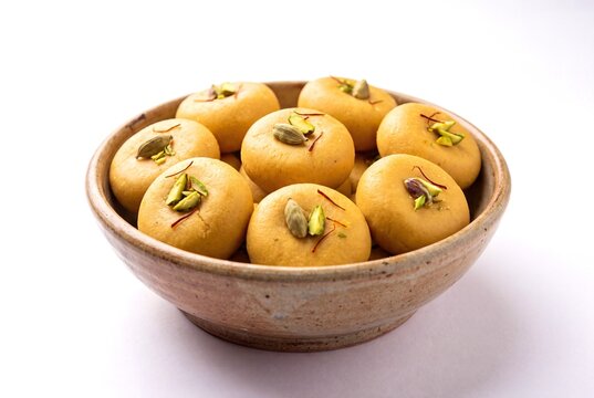 A Bowl of Traditional Indian Milk Peda Sweets Garnished with Saffron and Chopped Green Pistachios