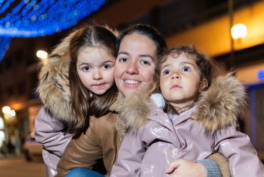 Mother and daughters enjoying outdoor christmas lights at night