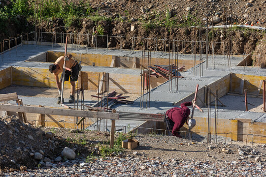 Construction Workers Pouring Concrete at Building Site During Foundation Work
