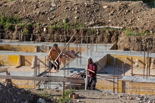 Construction Workers Pouring Concrete at Building Site During Foundation Work