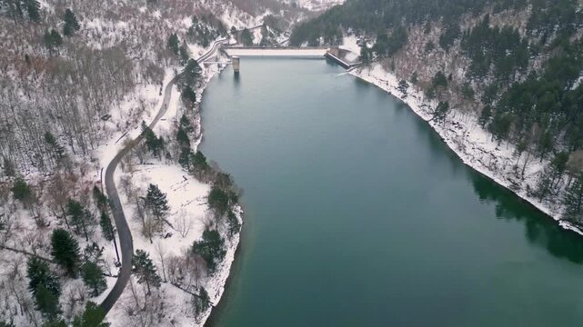 Aerial drone flying backwards revealing a winter dam