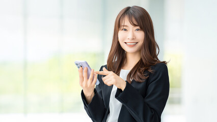 Fototapeta premium スマートフォンを使う笑顔の女性・ビジネスウーマン