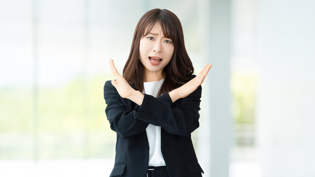 手でバツのポーズをして怒る女性・ビジネスウーマン