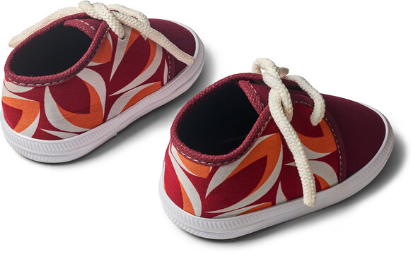 pair of patterned baby shoes isolated white background, red canvas footwear with white laces and rubber soles, angle view with shadow