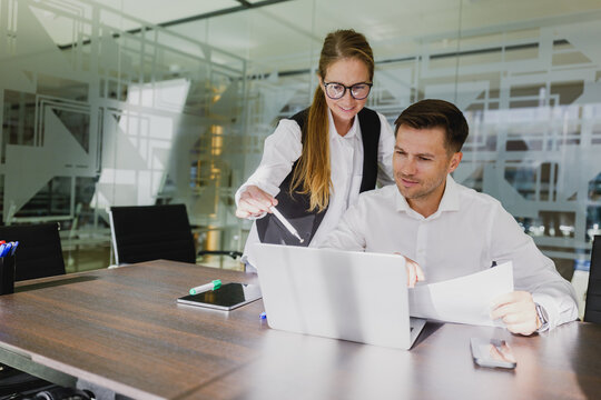 Business partners collaborate enthusiastically in a modern office space during a productive midday meeting over laptops and documents