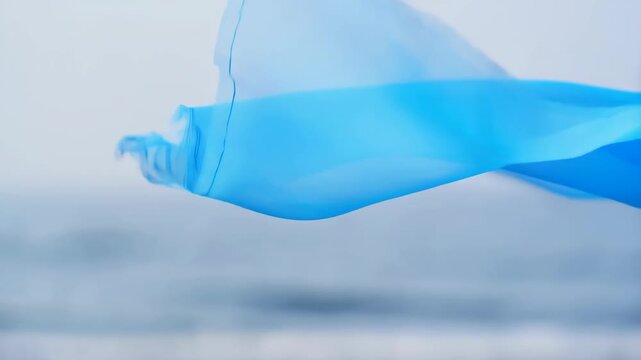 Static shot of light blue sheer chiffon fabric gently waving and flowing in air on white background