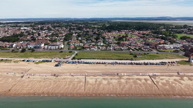 Cinematic aerial drone footage of Hayling Island Beach in Hampshire, England, featuring the expansive coastline, sandy and shingle beach, clear coastal waters