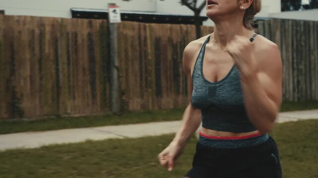 Female runner passing discarded paper cup along quiet fenced path