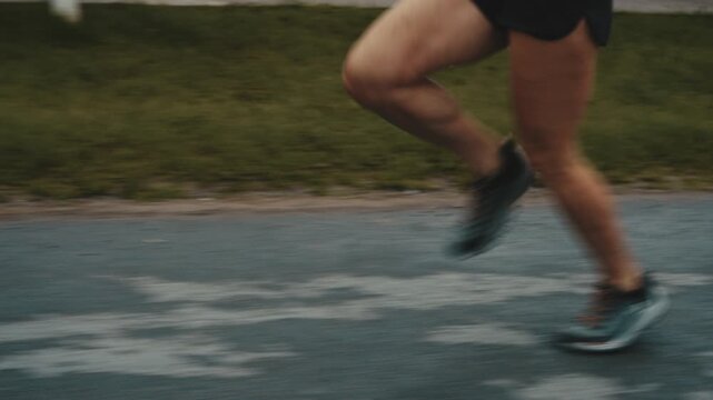 Close up of female runner's feet striking wet pavement near wooden fence