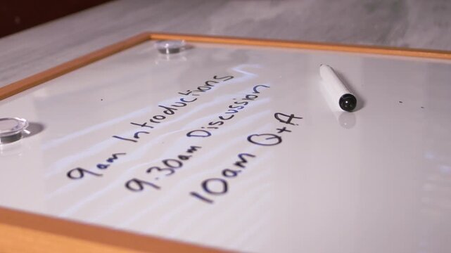 Pen landing on meeting schedule on whiteboard