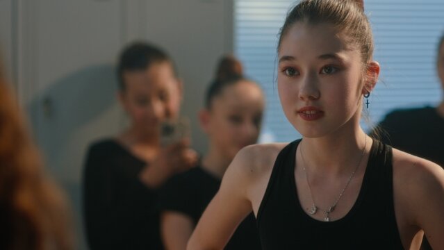 Harsh Conflict Within Children Rhythmic Gymnastics Team. Mean Girl Confronts Classmate in Locker Room, Using Smartphone as Tool Intimidation and Public Shaming. Concept of Bullying, Social Pressure.