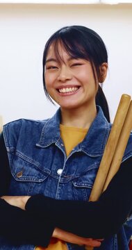 Japanese woman, teacher and face with drum sticks in class for taiko tradition, culture or practice. Portrait, asian musician or female person with smile for music lesson, sound or percussion art