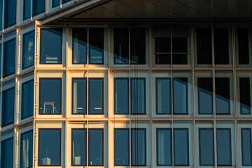 Obraz premium Modern Office Building Glass Facade with Diagonal Shadow and Sunset Light