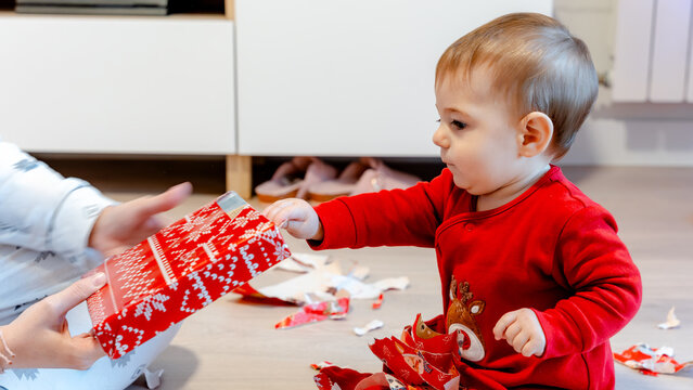 Baby opening Christmas present in festive pajamas