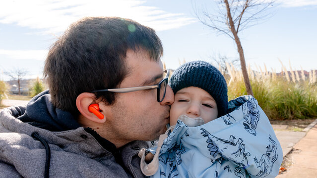Father kissing baby outdoors on a sunny day