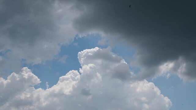 Clouds moving across the sky at noon with blue patches showing in between darker clouds