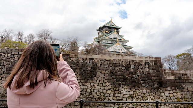 Tourist capturing Osaka Castle on a cloudy day