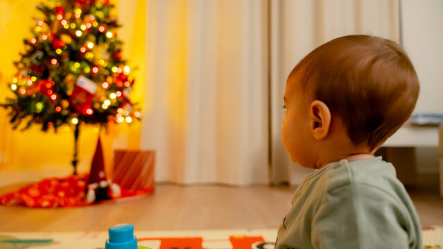 Baby admiring a festively lit Christmas tree