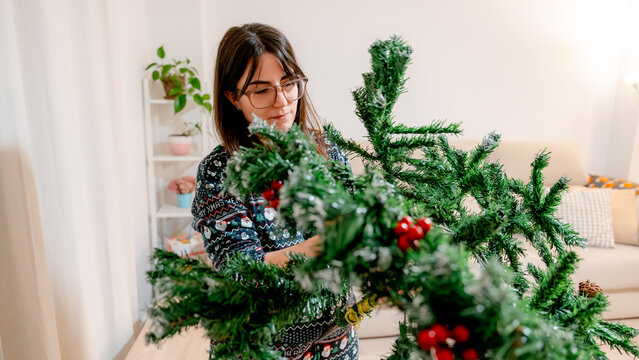 Woman assembling a Christmas tree in cozy living room