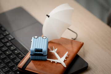Travel insurance concept. Close-up of a hand protecting travel essentials with an umbrella beside a laptop, symbolizing trip coverage, Travel, insurance, protection, security, vacation © Thitiporn