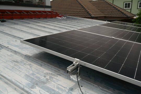 Solar Panels Installation on Metal Roof of Residential Home with Mounting Hardware Close Up