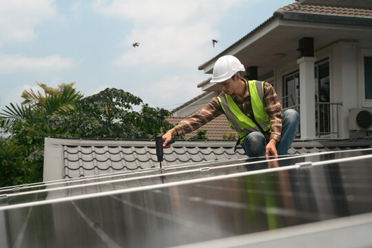 Technician Installing Solar Panels on Residential Home Rooftop with Power Drill