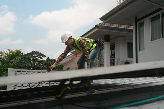 Solar Panel Installation Technician Working on Residential Rooftop in Safety Gear