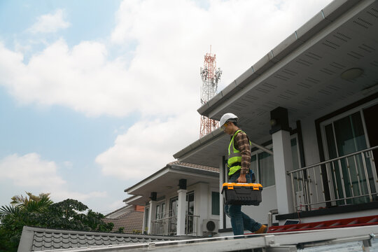 Solar Panel Technician Carrying Toolbox on Residential Rooftop During Installation Work