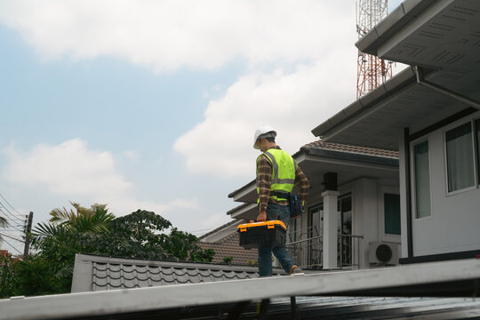 Solar Panel Technician Walking on Rooftop Carrying Toolbox for Home Installation