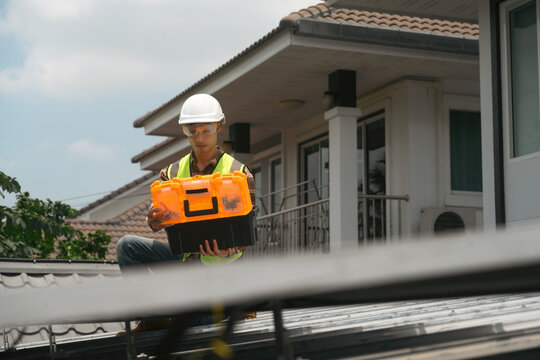 Solar Panel Technician Holding Toolbox on Residential Rooftop During Installation