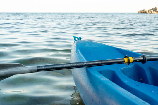 Blue kayak with paddle resting on calm ocean water surface