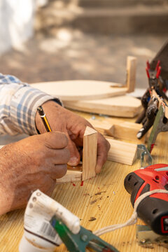 Carpenter marking a wooden joint at a workbench in Palamos