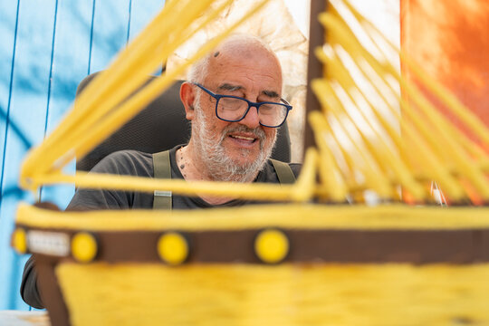 Elderly carpenter in Palamos crafting a wooden boat model