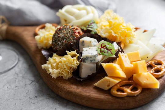 Artisanal cheese board with pretzel and herbs closeup