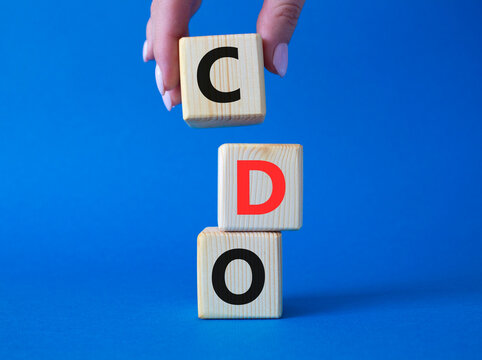 CDO - Collateralized Debt Obligation symbol. Wooden cubes with word CDO. Beautiful blue background. Businessman hand. Business and Collateralized Debt Obligation concept. Copy space.