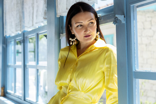 Woman in a bright yellow dress near a sunlit window