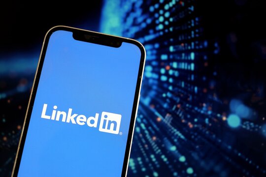 Salvador, Brazil - July 14, 2026: LinkedIn logo on a smartphone screen against a futuristic digital background. Concept of AI-generated content on social media. Linkedin and AI.