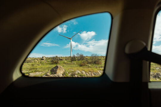 Scenic view of wind turbine through car window