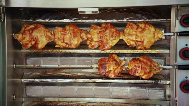 Whole chickens slowly roasting on spits, turning to achieve golden-brown skin, ready for serving daily