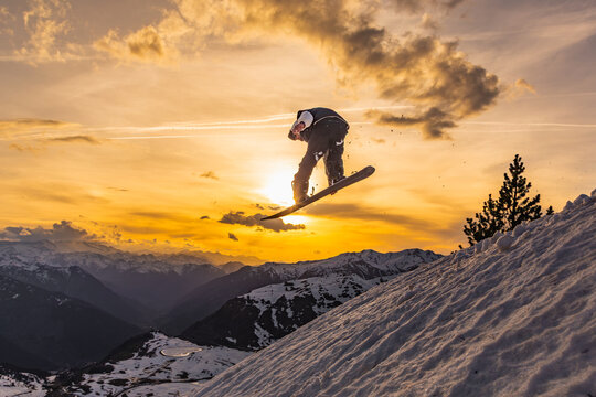 Snowboarder jumping against sunset mountain backdrop