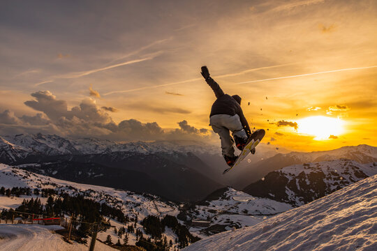 Snowboarder soaring through sunset in winter mountains