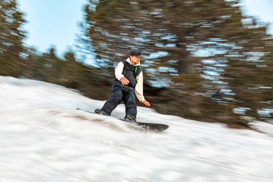 Snowboarder gliding down snowy slope at sunset