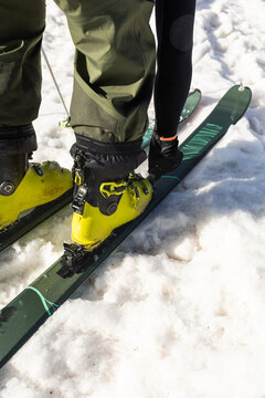 Skier fastening boots on snow-covered mountain slope