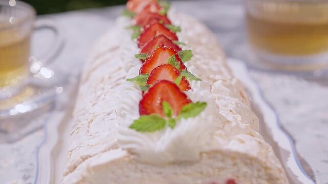 Close-up of Pavlova dessert topped with whipped cream and fresh strawberries. Crispy meringue texture and vibrant berries create an elegant gourmet presentation.