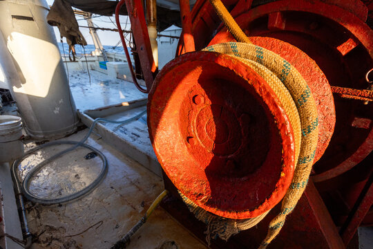 Rusty winch and coiled rope on working fishing boat deck