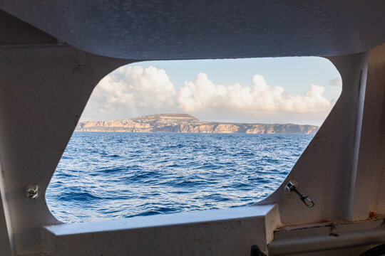 Seaside cliff view through boat window on calm blue sea