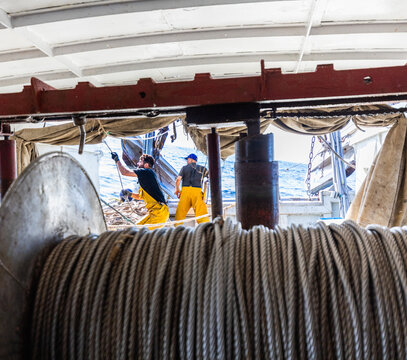 Fishermen working on deck with rope winch at sea